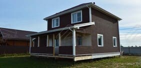 Вид сбоку на дом с окнами и отделкой фасада 