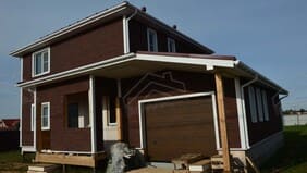 Дом в процессе отделки, вид спереди с крыльцом